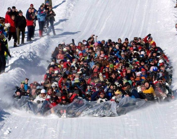 CRAZY SNOW FUN - HUGE CROWD SLIDES DOWN SLOPE ON LARGE PLASTIC SHEET!